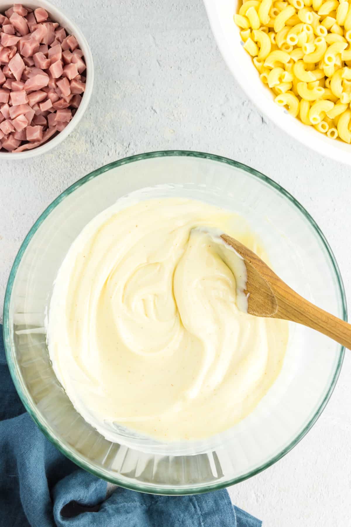 Bowl with spoon mixing dressing for pasta salad