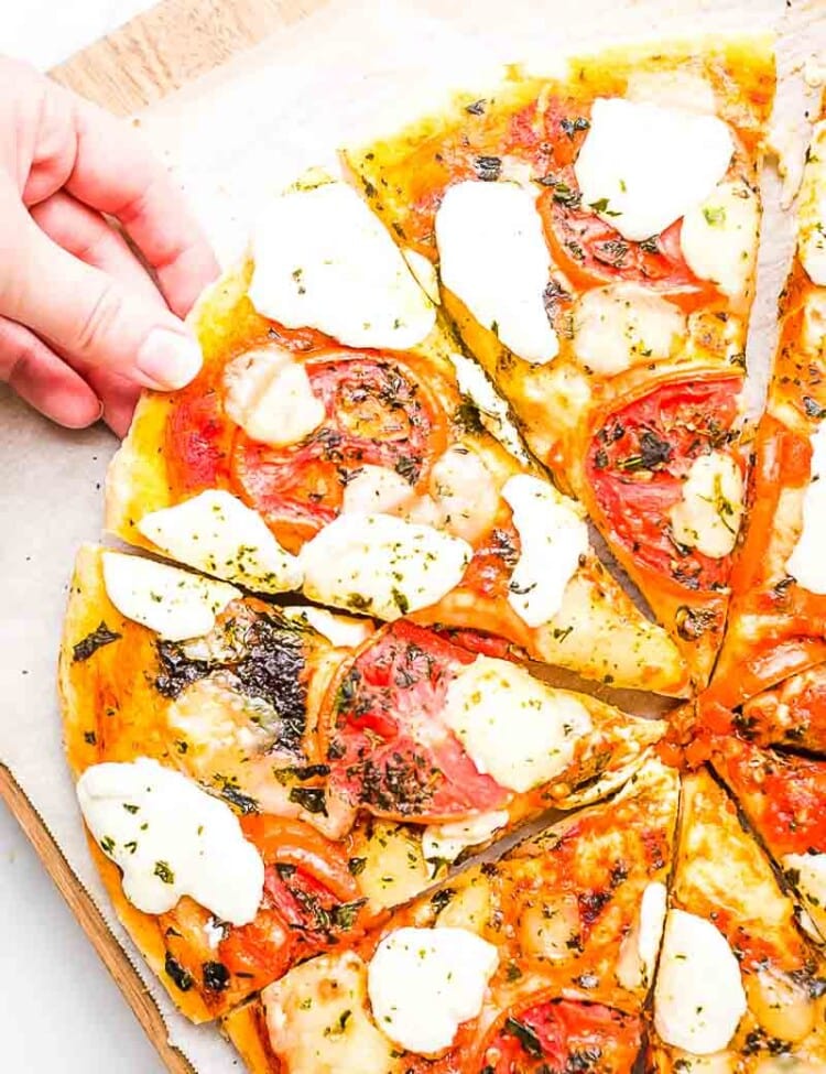 Hand taking slice of Margherita Pizza