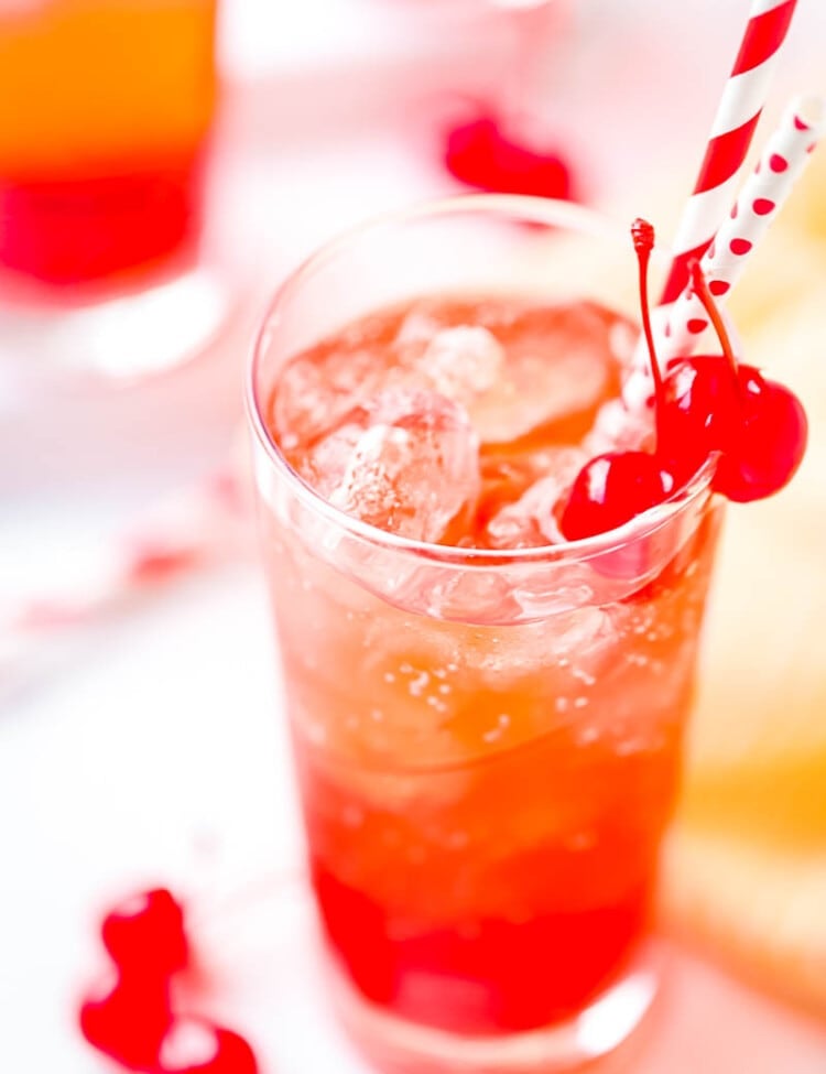 Tall Glass of Shirley Temple with cherries and two straws