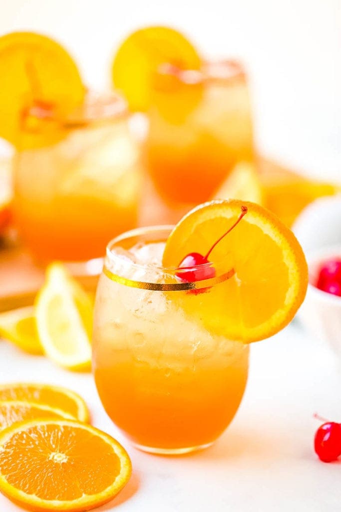 Sour Drink with oranges and cherries garnishing the glass