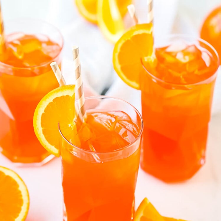 Three glasses of Aperol Spritz with orange slices