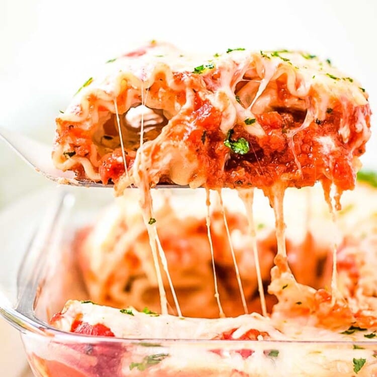 Spatula with Lasagna Roll Up on it lifting out of casserole with cheese pull