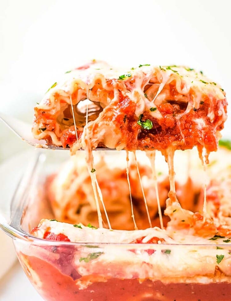 Spatula with Lasagna Roll Up on it lifting out of casserole with cheese pull