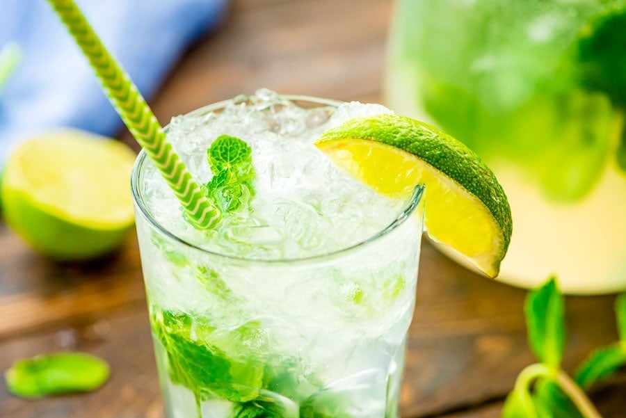 Mojito Cocktail in glass with ice, lime wedge, and green straw