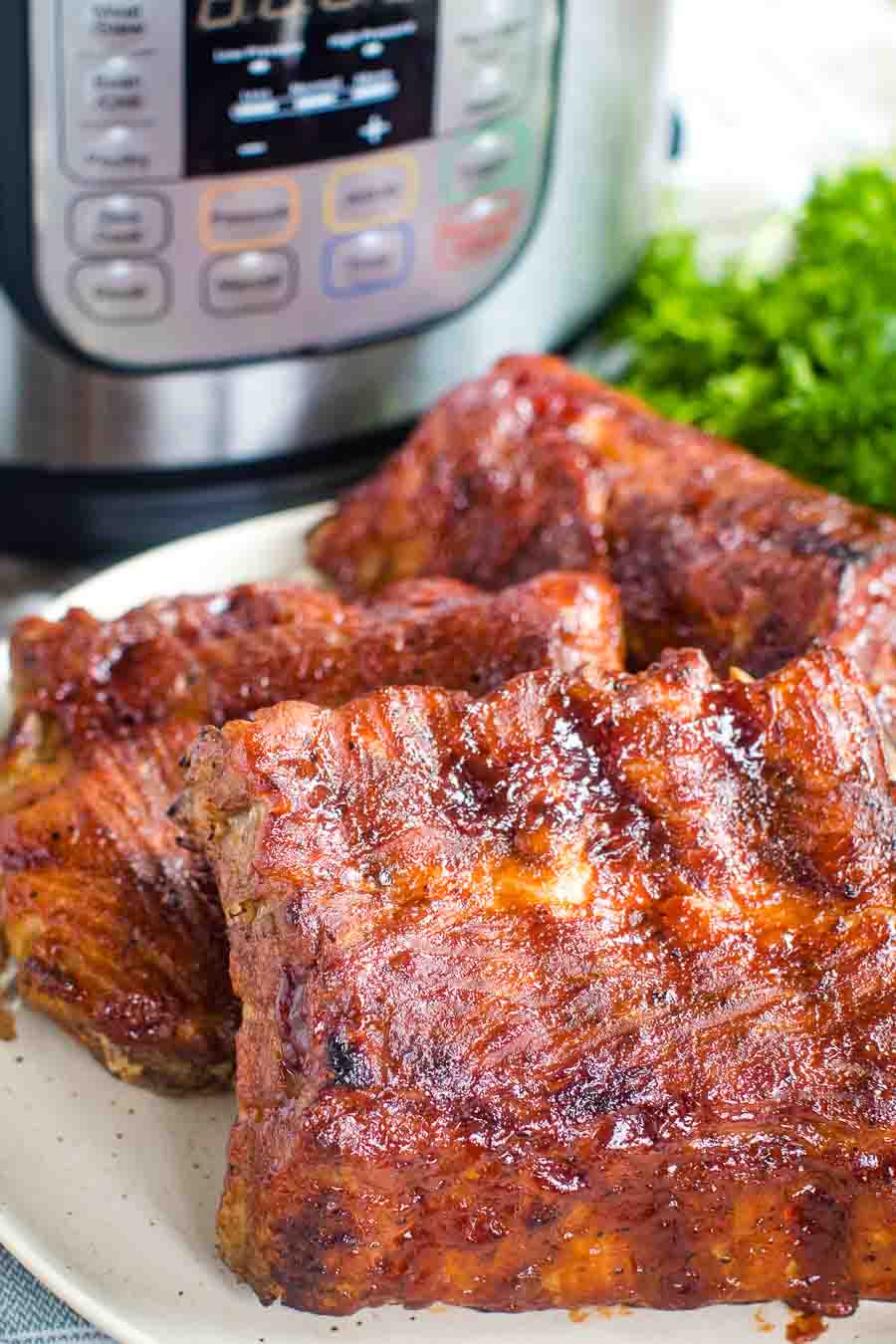 A plate with ribs on it and an Instant Pot in background