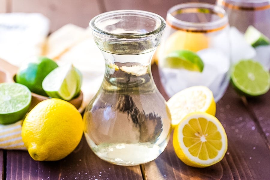 Homemade Sweet and Sour Mix in glass jar with slice lemons and limes next to it