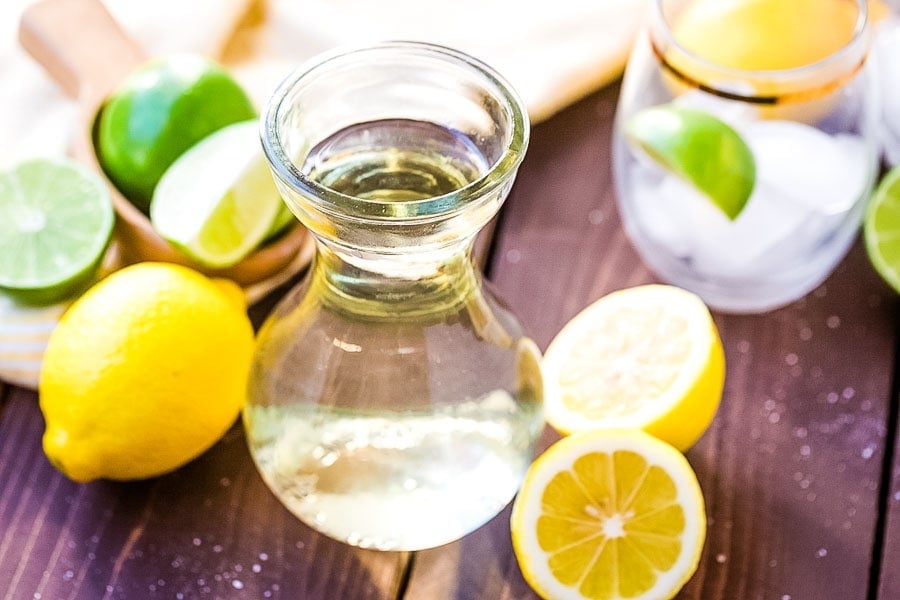 Jar of homemade Sour Mix with lemons and limes beside it