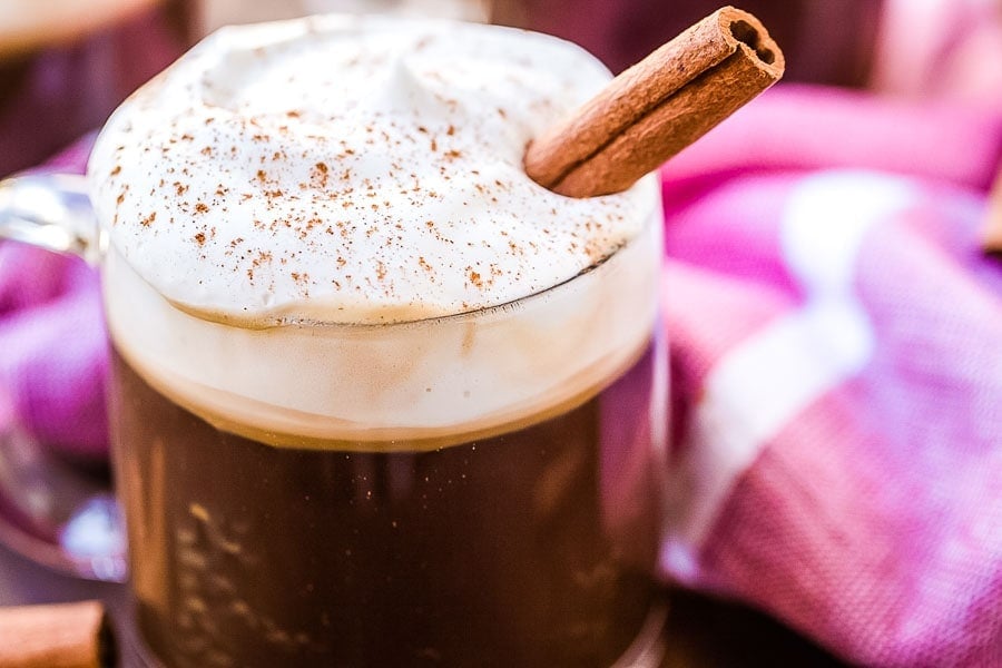 Mug of Irish Coffee topped with whipped cream, cinnamon and a cinnamon stick