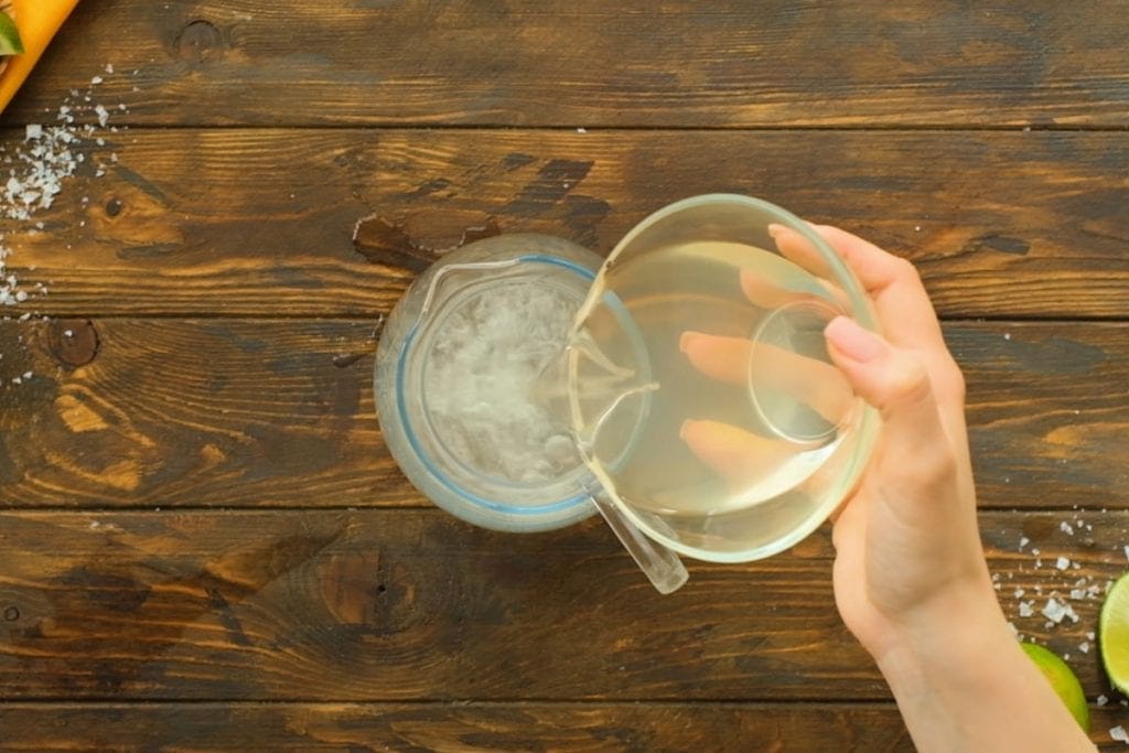 Pouring a bowl of alcohol into glass pitcher for drinks