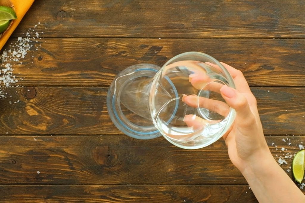 Pouring alcohol into glass pitcher for Margaritas.