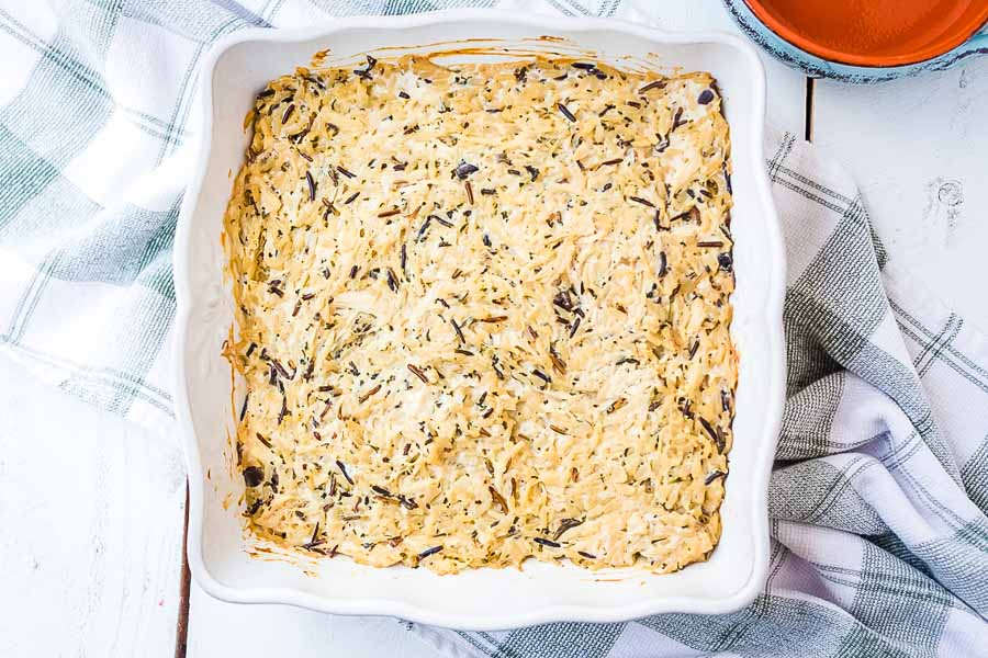 White baking dish with prepared casserole on top of blue checkered napkin