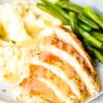 Slices of turkey, mashed potatoes, green beans, and gravy on a plate