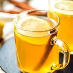 Glass mugs of Hot Toddy with lemon slices and cinnamon sticks