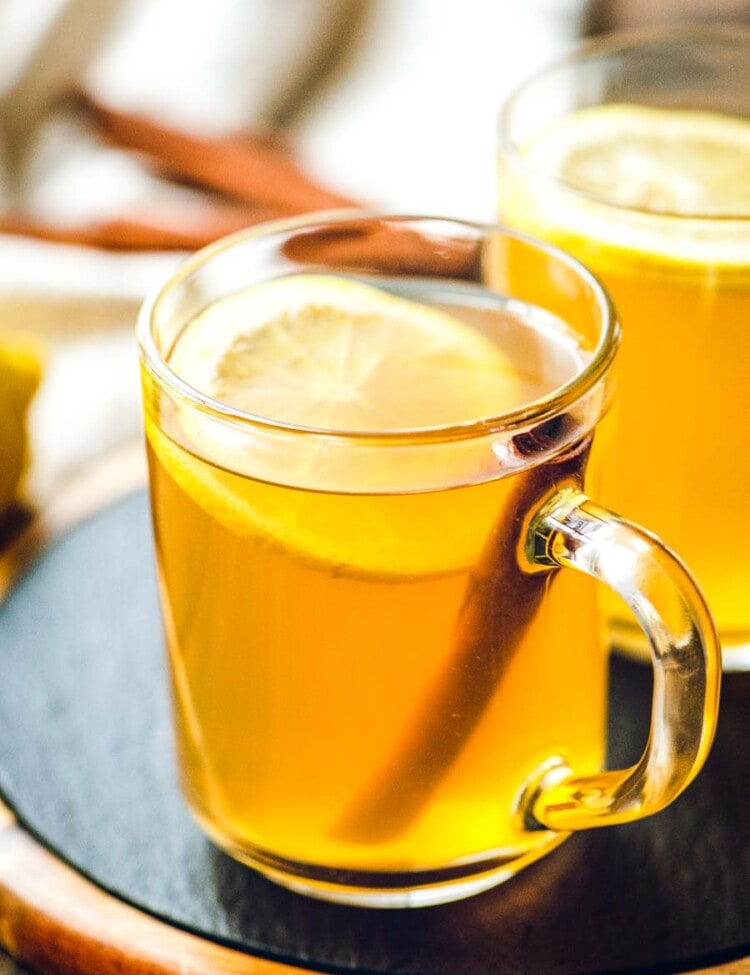 Glass mugs of Hot Toddy with lemon slices and cinnamon sticks