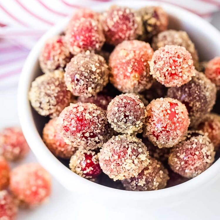 bowl of sugared cranberries with a red and white striped napkin in the background