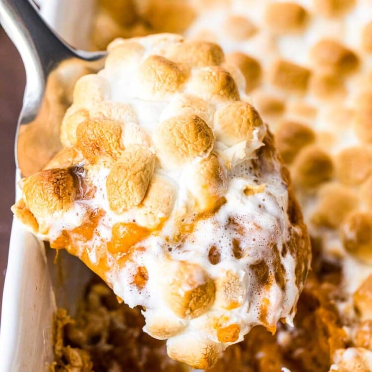 Metal spoon scooping sweet potato casserole out of the baking dish