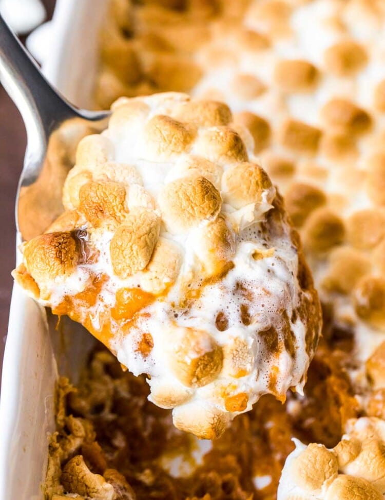 Metal spoon scooping sweet potato casserole out of the baking dish