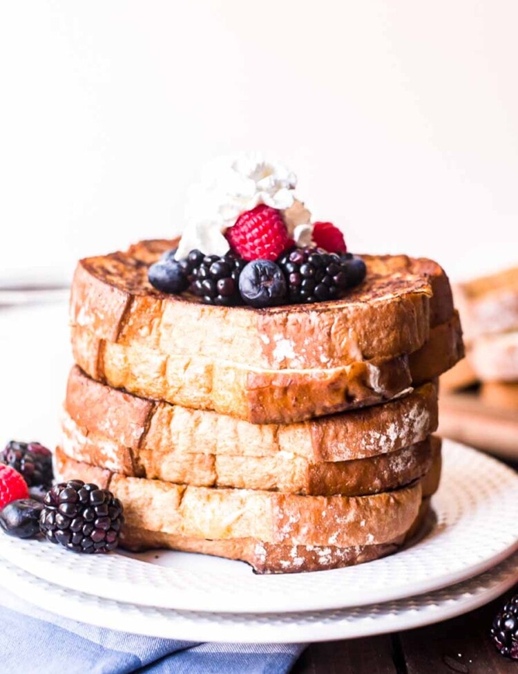 Stack of stuffed french toast topped with whipped cream and berries on a plate