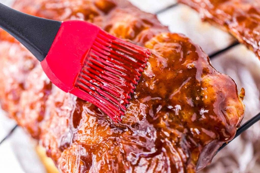 Ribs being brushed with BBQ Sauce