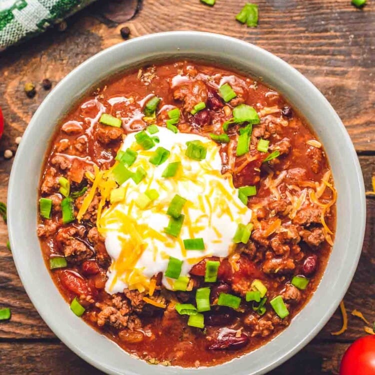 Bowl of Instant Pot Chili topped with sour cream, shredded cheese, and chives