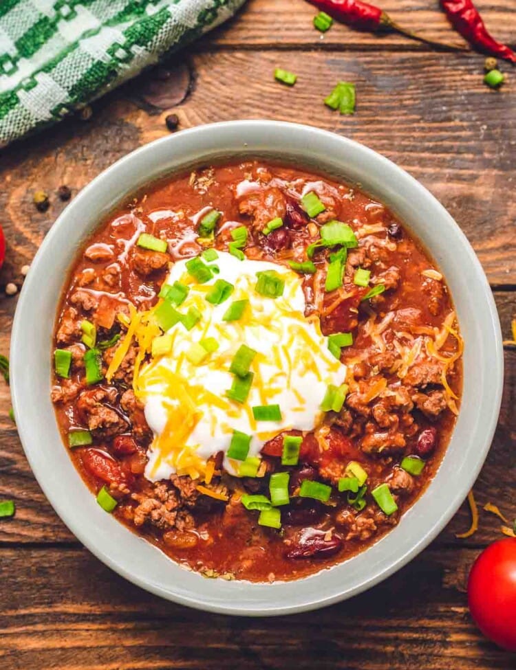 Bowl of Instant Pot Chili topped with sour cream, shredded cheese, and chives