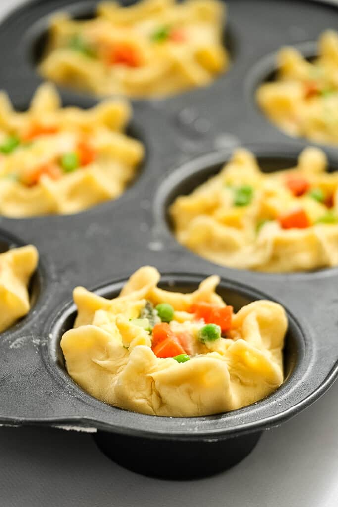 Biscuit dough in muffin tin with pot pie filling