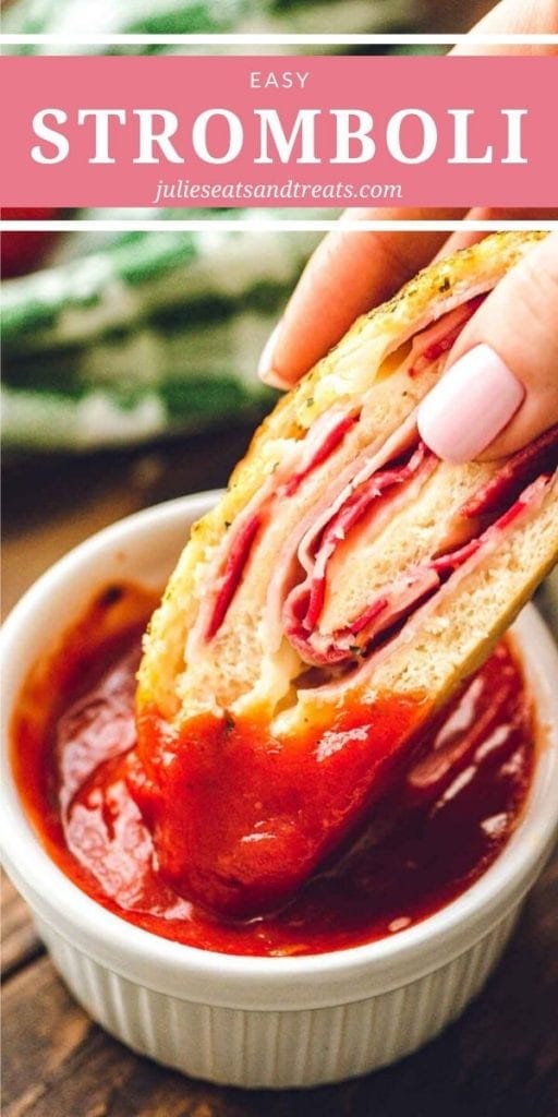 Hand dipping a slice of stromboli into marinara sauce