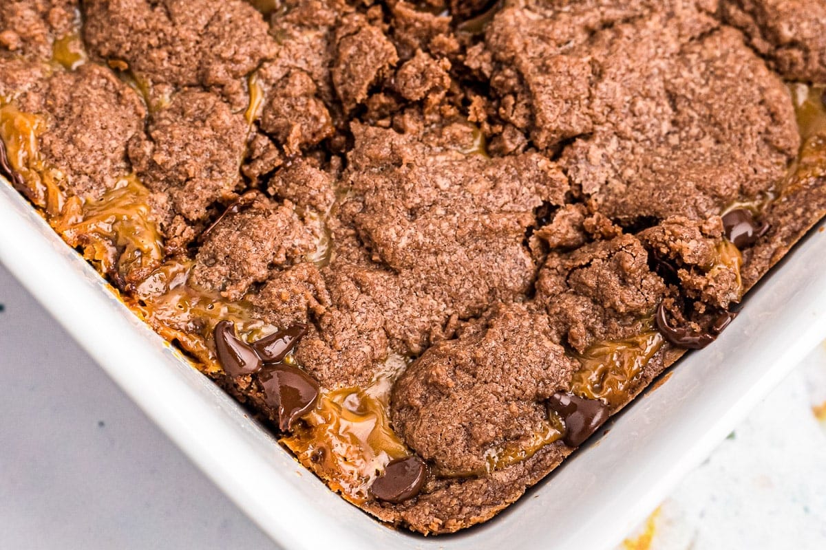 Overhead image of white baking dish with chocolate caramel brownies in it.