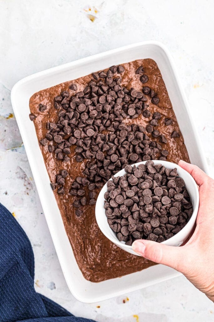 Overhead image of chocolate chips being sprinkled on brownie crust.