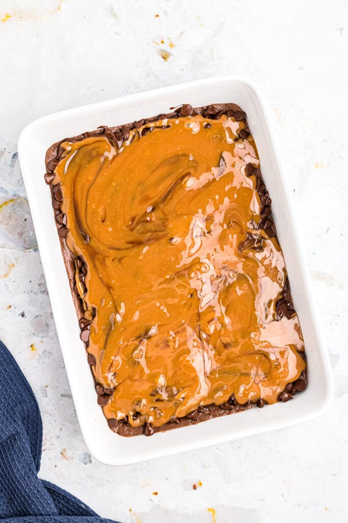 Overhead image of caramel being poured on brownie crust.