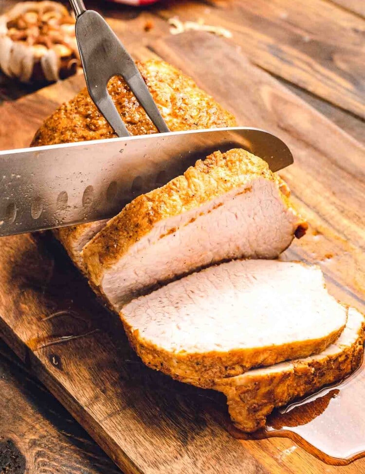Pork loin being sliced on a wood cutting board