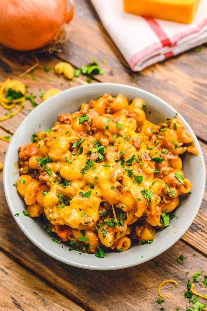 Bowl with American Goulash topped with cheddar cheese and parsley