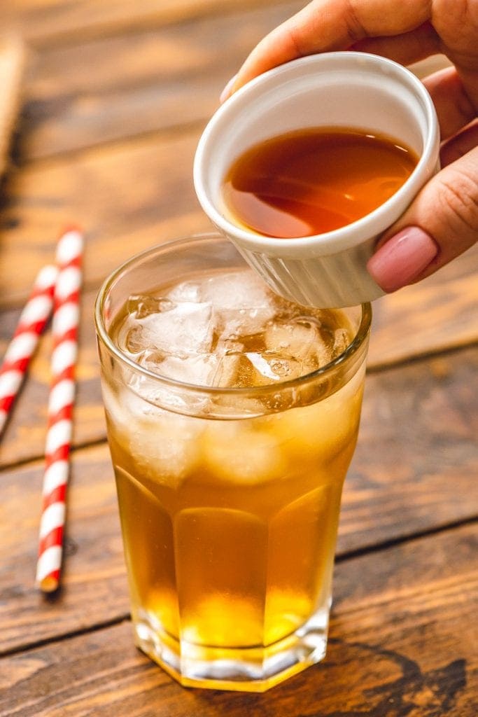 Dish pouring iced tea into a glass with lemonade and ice