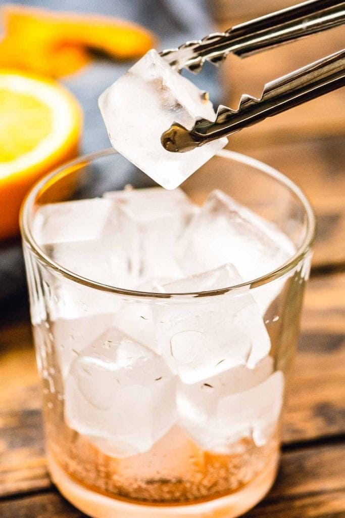 Tongs putting ice into a glass