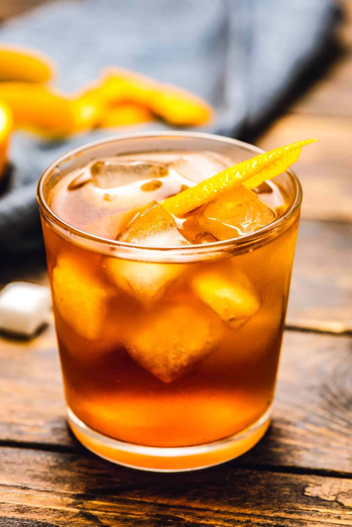 An old fashioned in a lowball glass with a large ice cube and an orange  peel