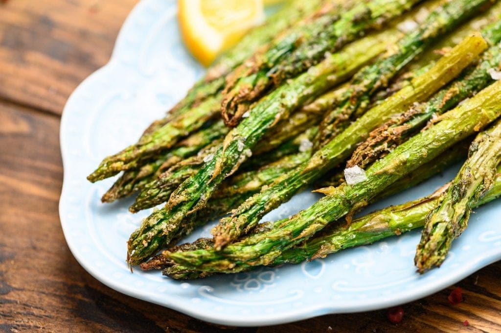 Roasted Asparagus on blue plate with lemon slices for garnish