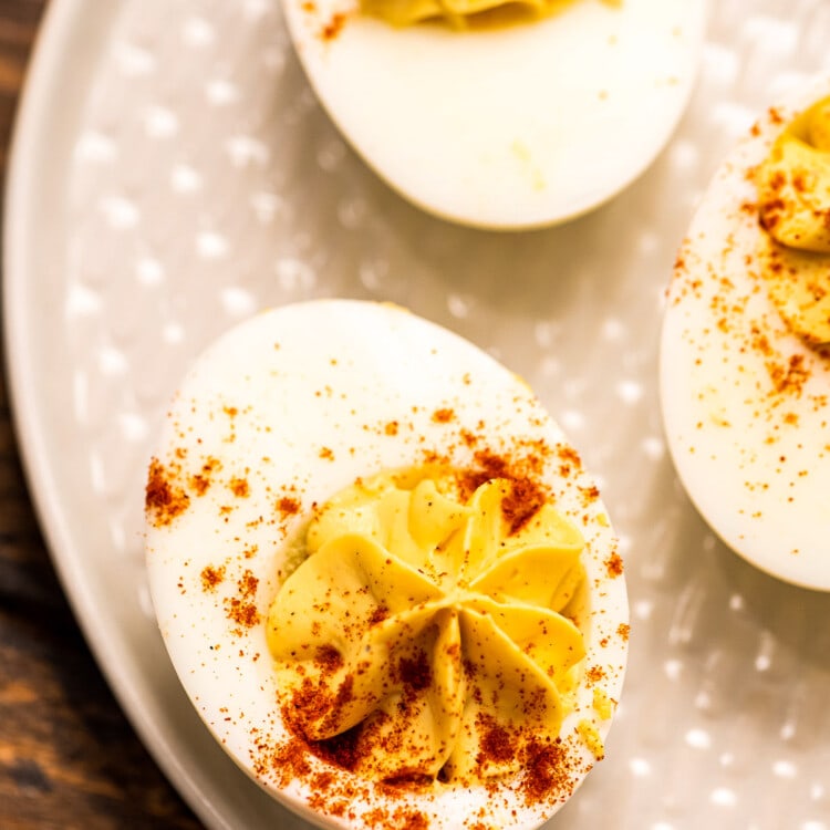 Overhead image of off white plate with deviled eggs garnished with paprika on it