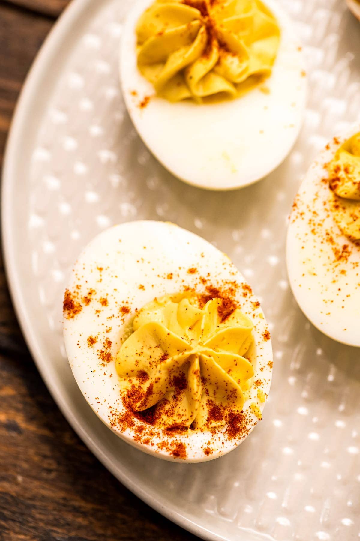 Overhead image of off white plate with deviled eggs garnished with paprika on it
