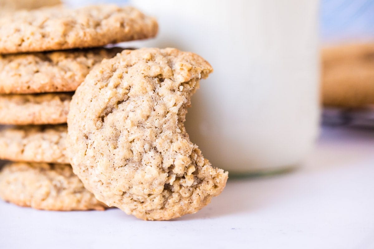 Cookie with a bite missing leaning up against a glass bottle with milk in it