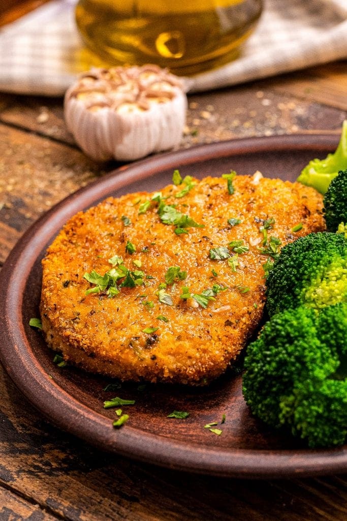 Plate with bread pork chops and broccoli on it