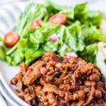 White plate with baked beans, salad on light background