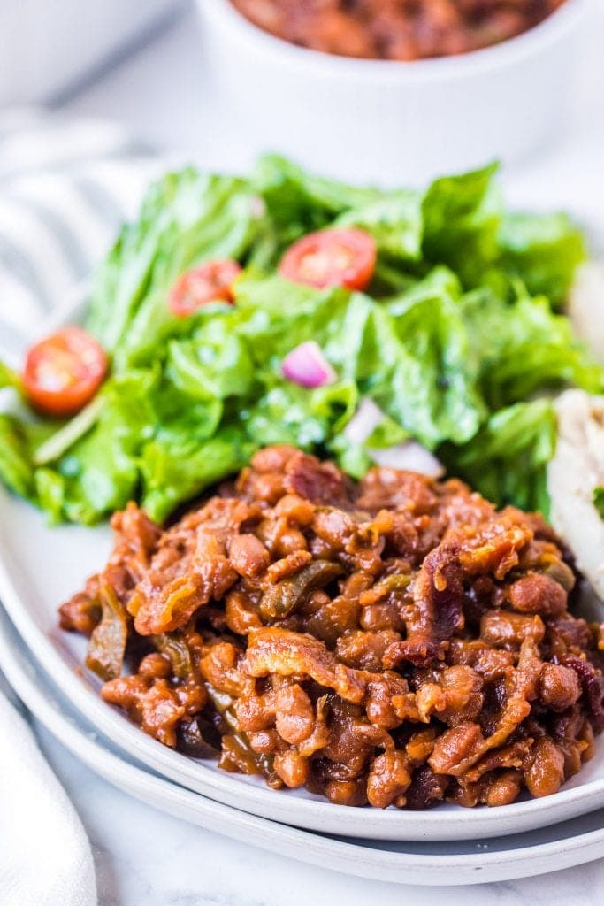 White plate with baked beans, salad on light background