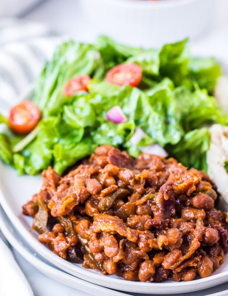 White plate with baked beans, salad on light background