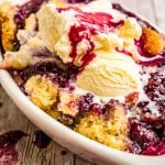 White dish with cobbler in it topped with ice cream melting