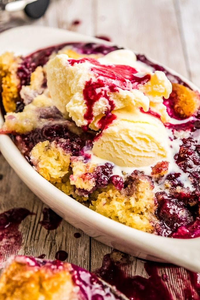 White dish with cobbler in it topped with ice cream melting 