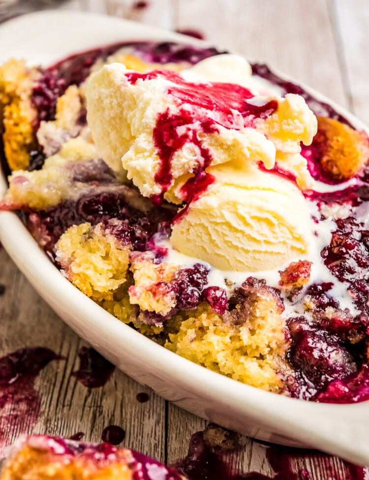 White dish with cobbler in it topped with ice cream melting