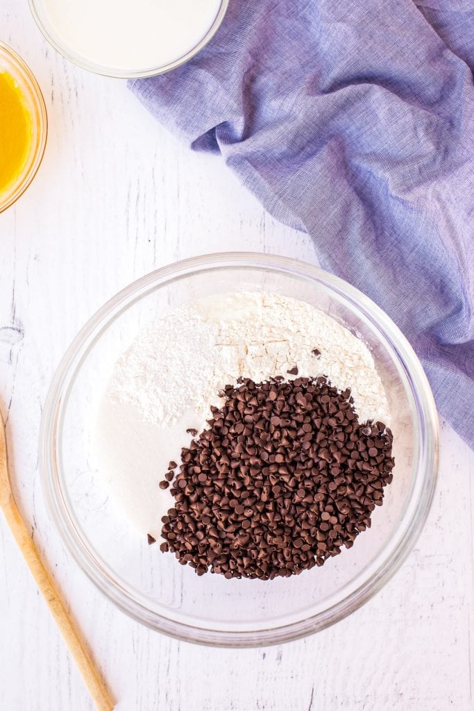 Bowl of dry ingredients like flour and chocolate chips in glass bowl