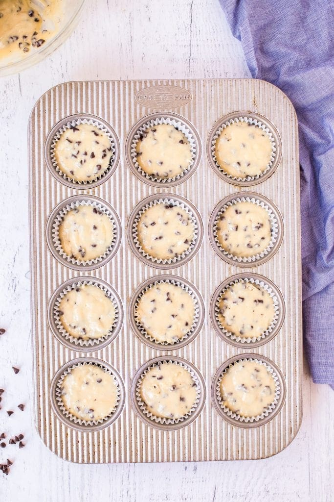 Muffin tin with muffin liners full of chocolate chip muffin batter