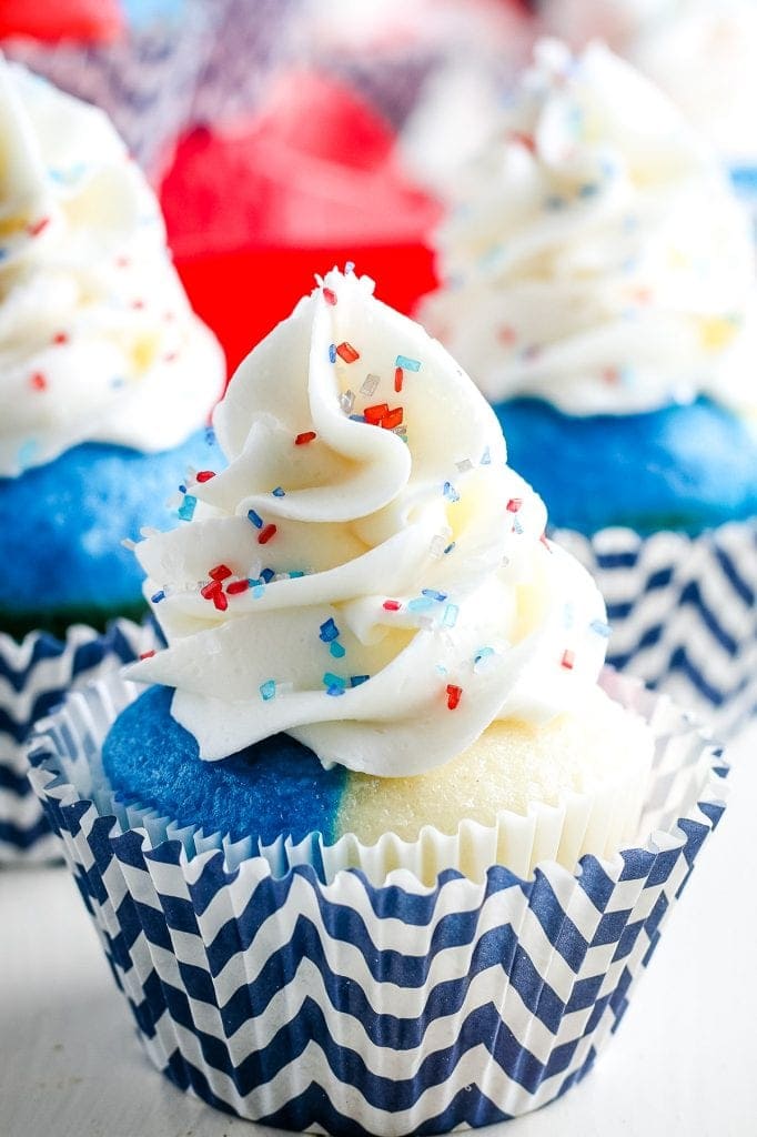 Red white and blue cupcake with white frosting and sprinkles in a chevron blue and white cupcake liner