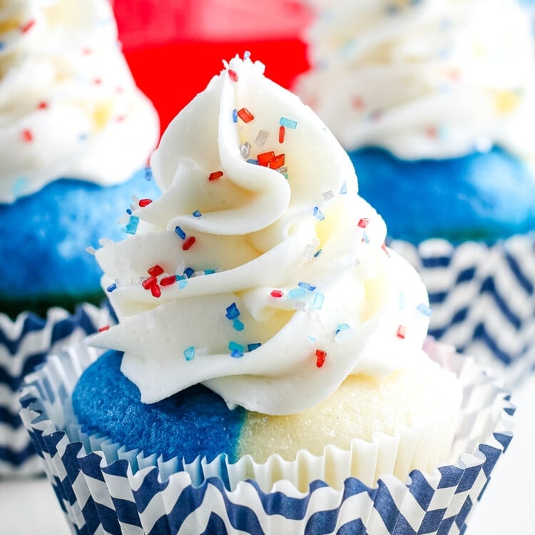 Red white and blue cupcake with white frosting and sprinkles in a chevron blue and white cupcake liner
